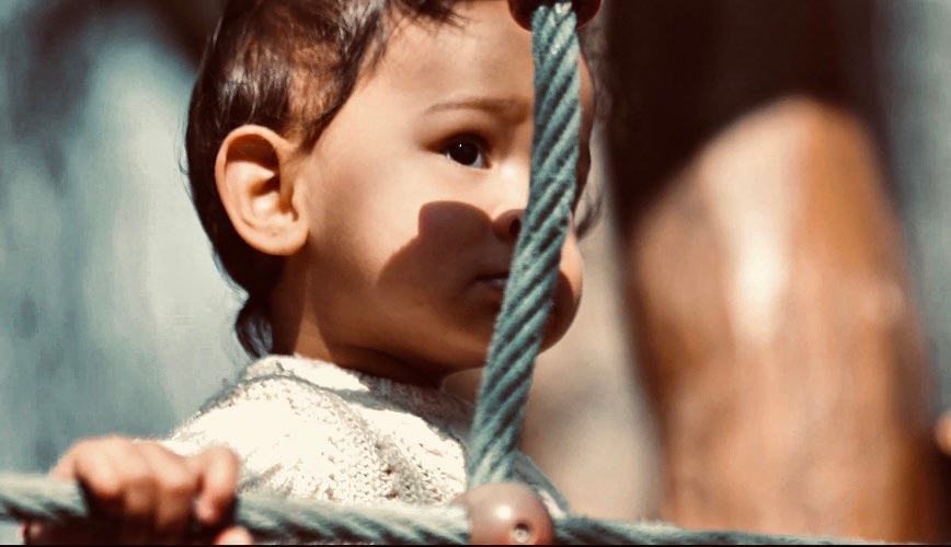 Close-up of a toddler on a playground climbing rope
