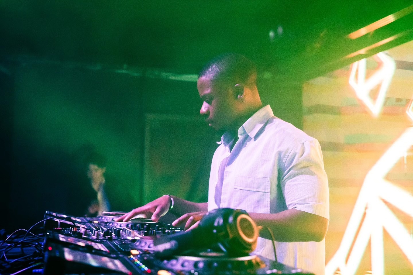 DJ performing under green stage lighting